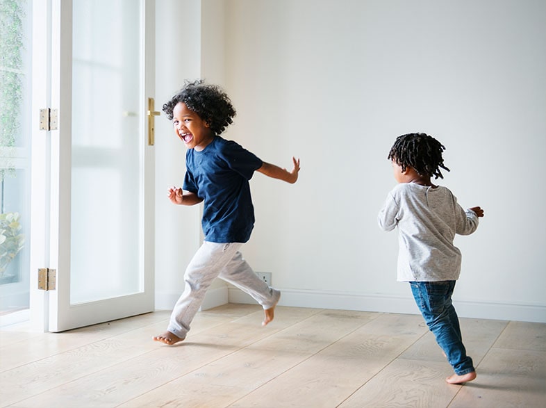 Two young children skipping indoors