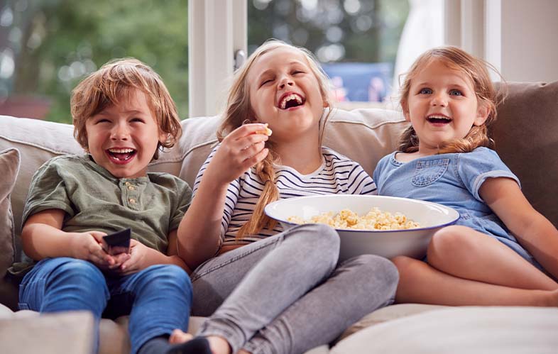 Three laughing kids sitting on a couch