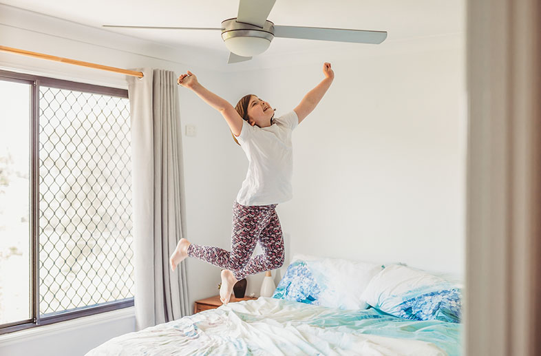 Happy child jumping on a bed