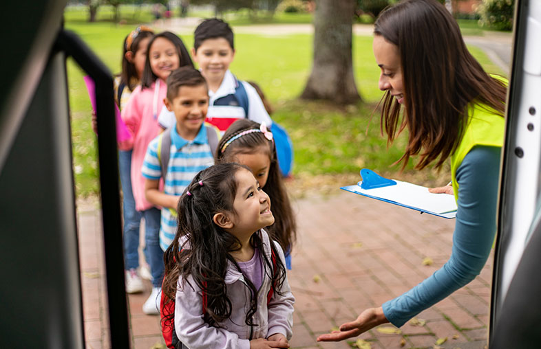 A line of smiling children getting on a bus