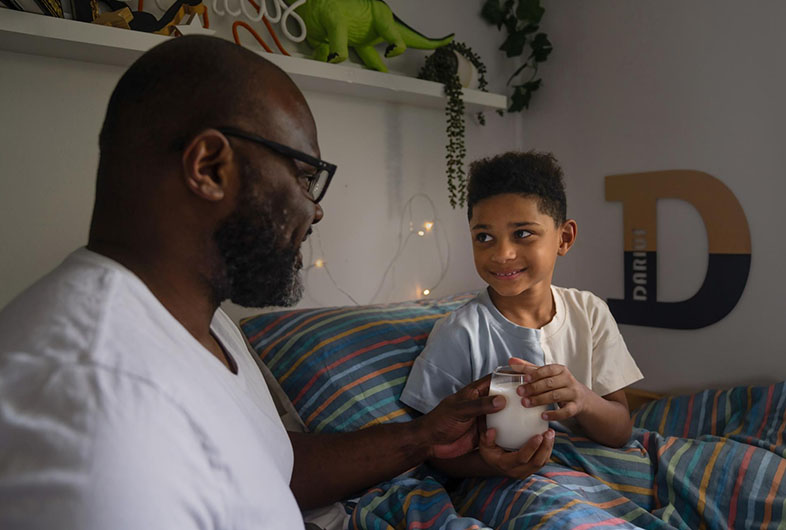 Dad handing his son a glass of milk