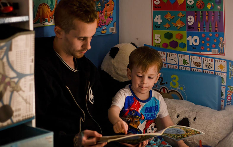 Dad and son reading a book in bed