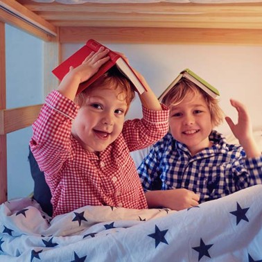 Two smiling kids with books on their heads