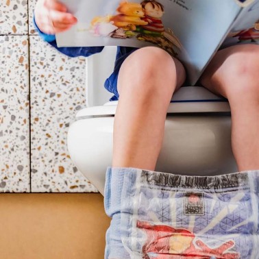 Boy on a toilet reading a book
